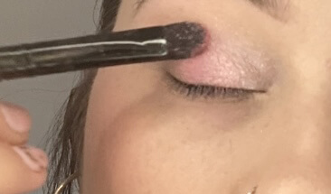 Application du fard rose irisé sur le coin interne de l'œil
